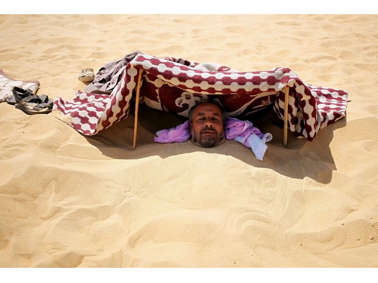 Kamēr citi vasarā veldzi meklē pie jūras, tikmēr Ēģiptē cilvēki dodas smilšu vannā.  Foto: Reuters/ Scanpix