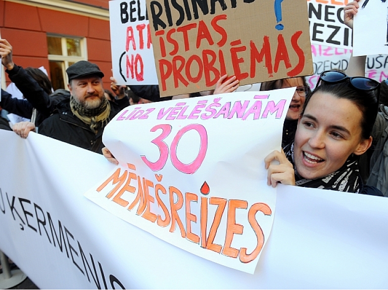 Ap 100 cilvēku ar dažādiem saukļiem un plakātiem pie Saeimas protestēja pret grozījumiem Reproduktīvās veselības likumā, kas paredz ierobežot nedzemdējušu sieviešu iespējas ziedot olšūnas.