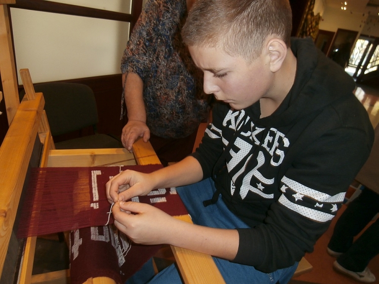 Pociema mazpulcēni piedalās himnas jostas aušanā

