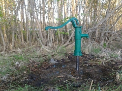 Rokas ūdens pumpis uz spices akas dārza