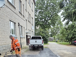 izmanto vibrācijas plāksni, lai sablīvēt uzklāto asfaltu būvniecības objektā.