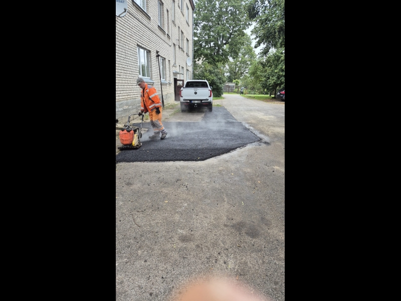 izmanto vibrācijas plāksni, lai sablīvēt uzklāto asfaltu būvniecības objektā.