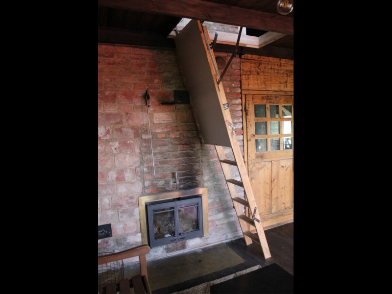 Koka kāpnes un kamīns koka mājas interjerā