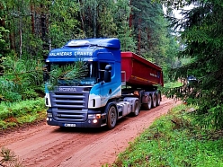 Scania kravas automašīna pārvadā grants pa meža ceļu