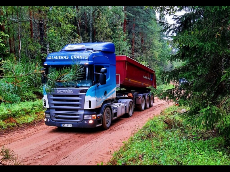 Scania kravas automašīna pārvadā grants pa meža ceļu